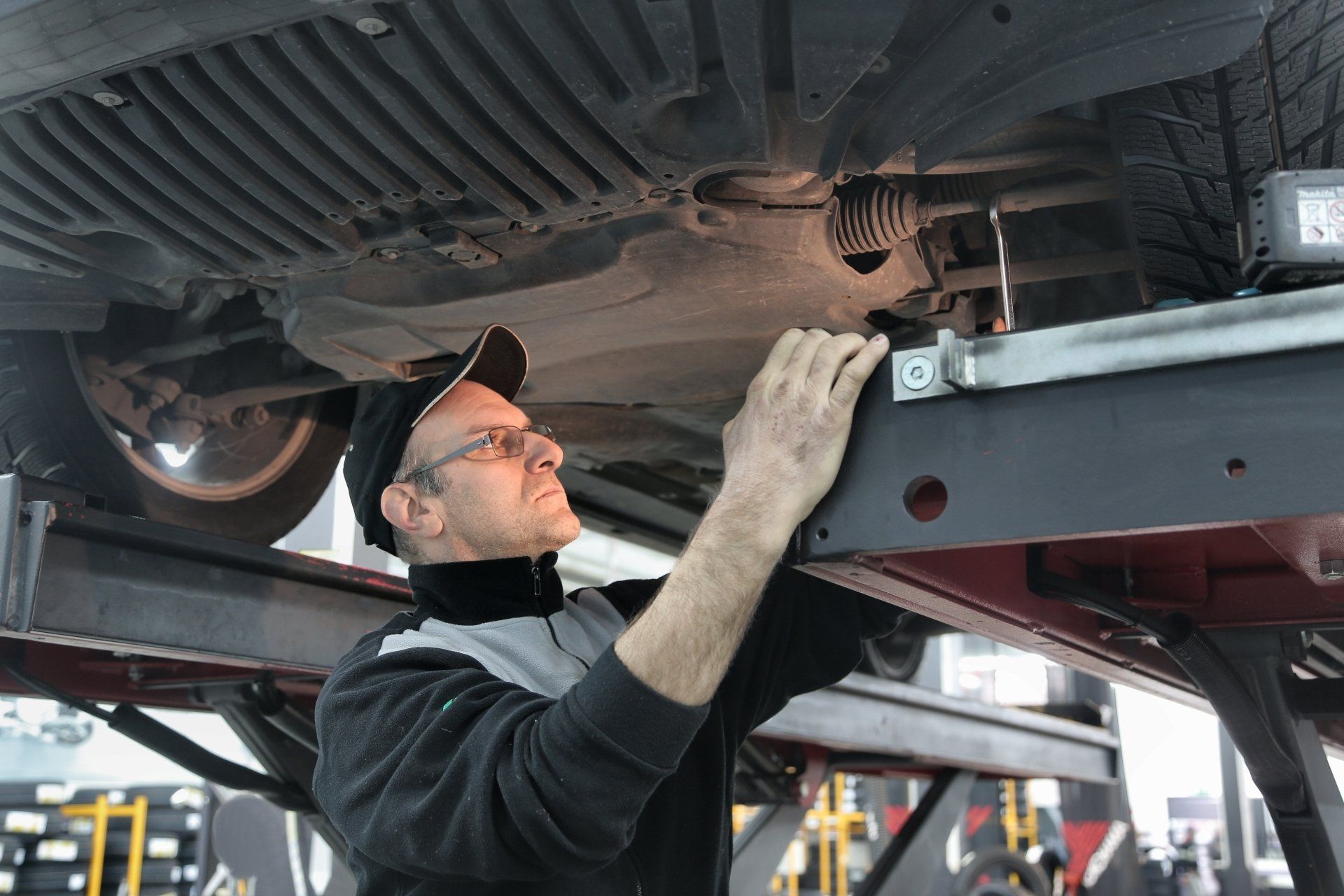Mechanic inspecting the underside of a car on a lift